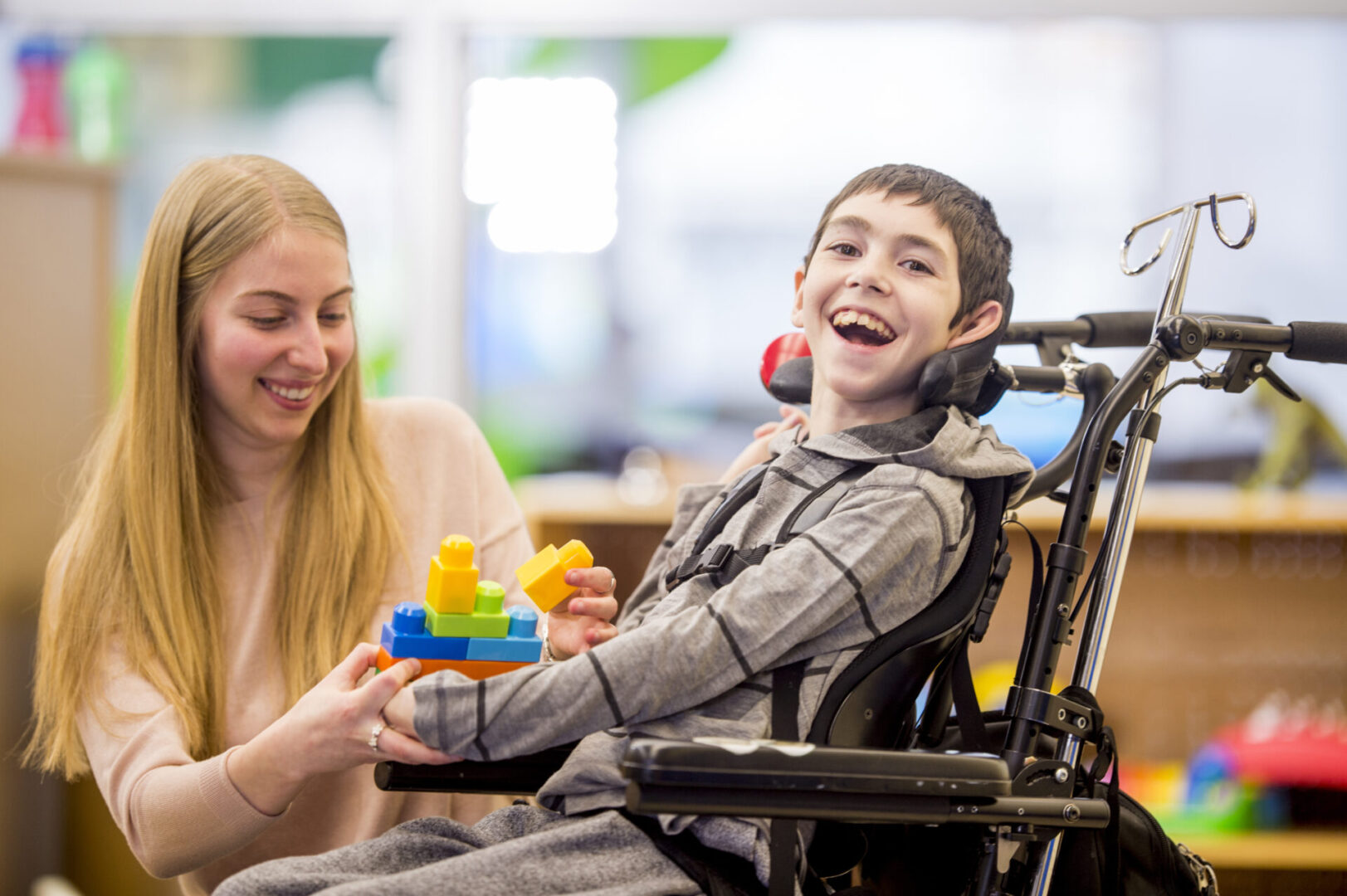 A boy in a wheelchair smiling at the camera.
