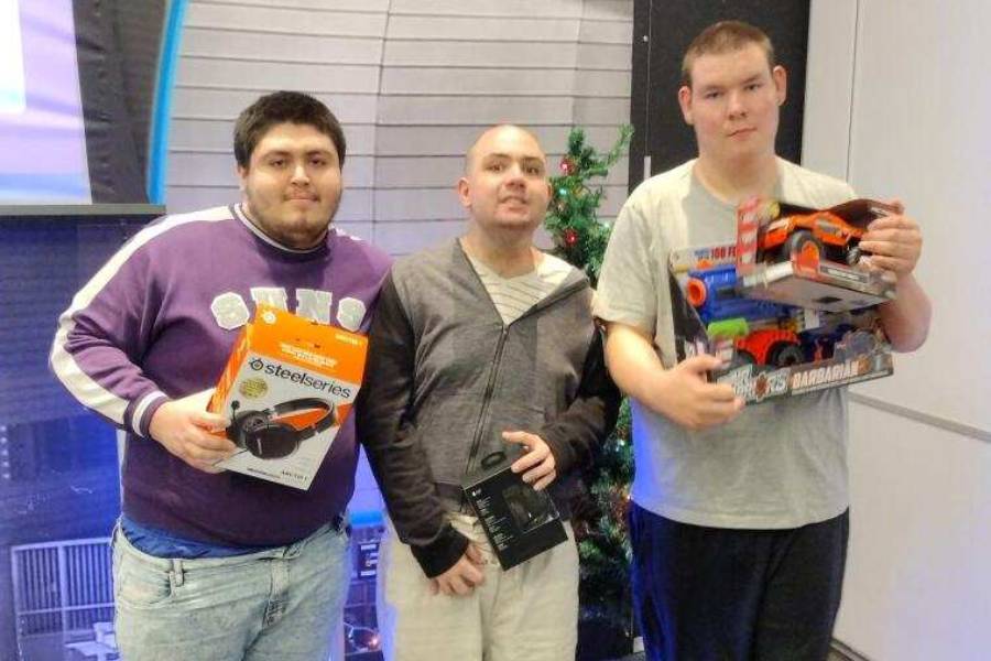 Three men holding up toys in a room.