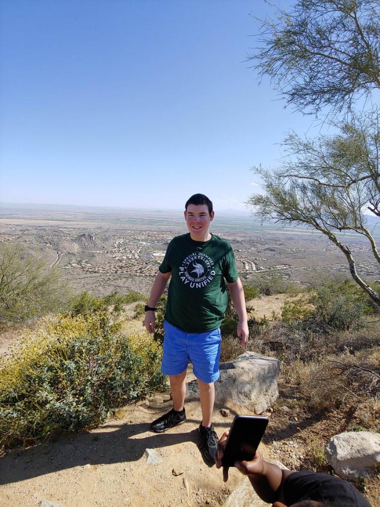 A man standing on top of a hill with trees in the background.