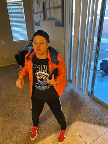 A young man in an orange jacket holding a nintendo wii controller.