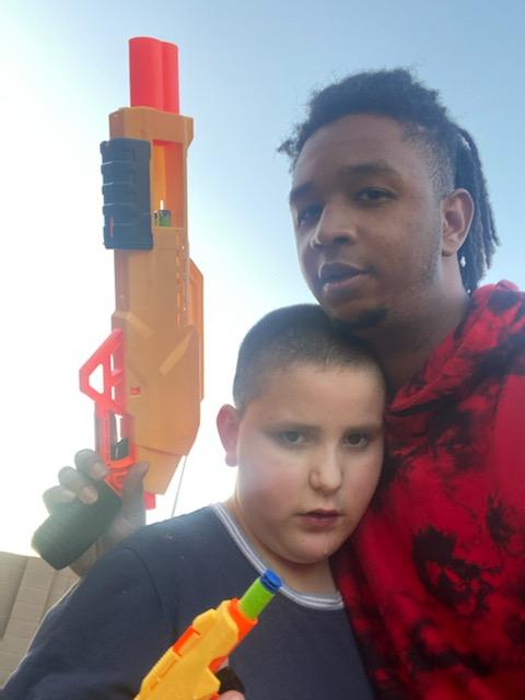 A man and boy posing for the camera with a toy gun.