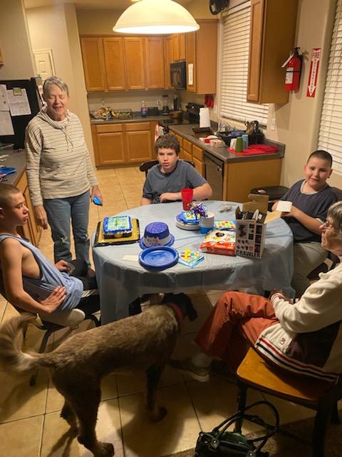 A group of people sitting around a table with cake.