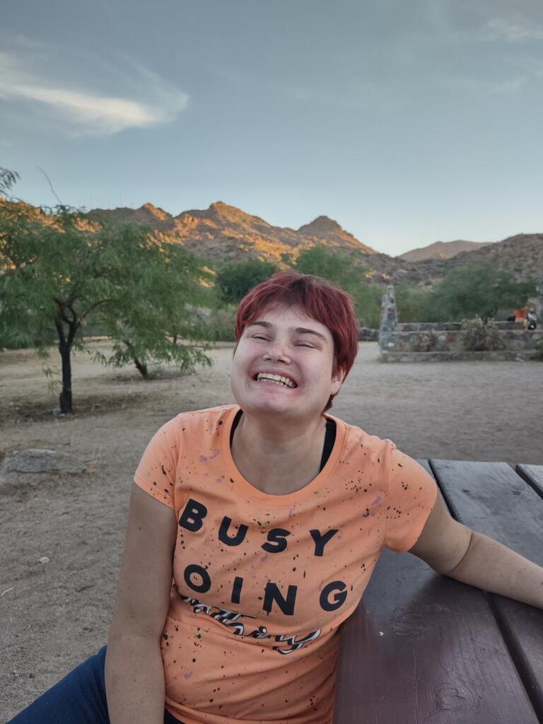 A woman sitting on top of a wooden bench.