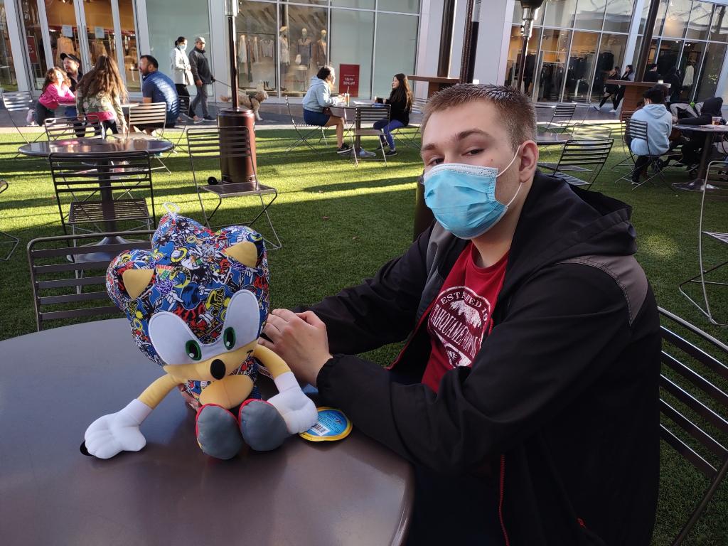 A man sitting at a table with a stuffed animal.
