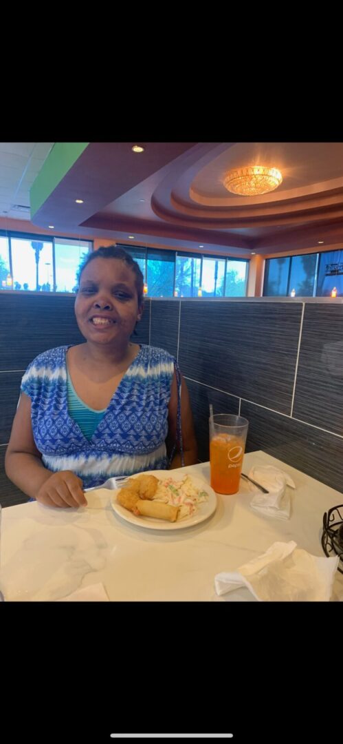 A woman sitting at the table with food in front of her.