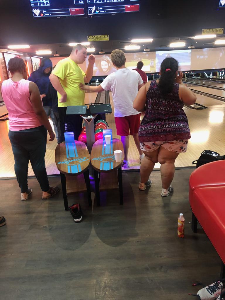 A group of people standing around bowling alley.