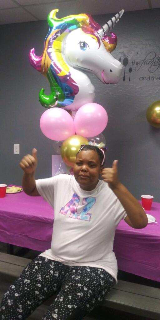 A woman giving two thumbs up at a birthday party.