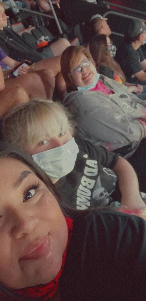 A group of people wearing masks and sitting in the middle of a room.