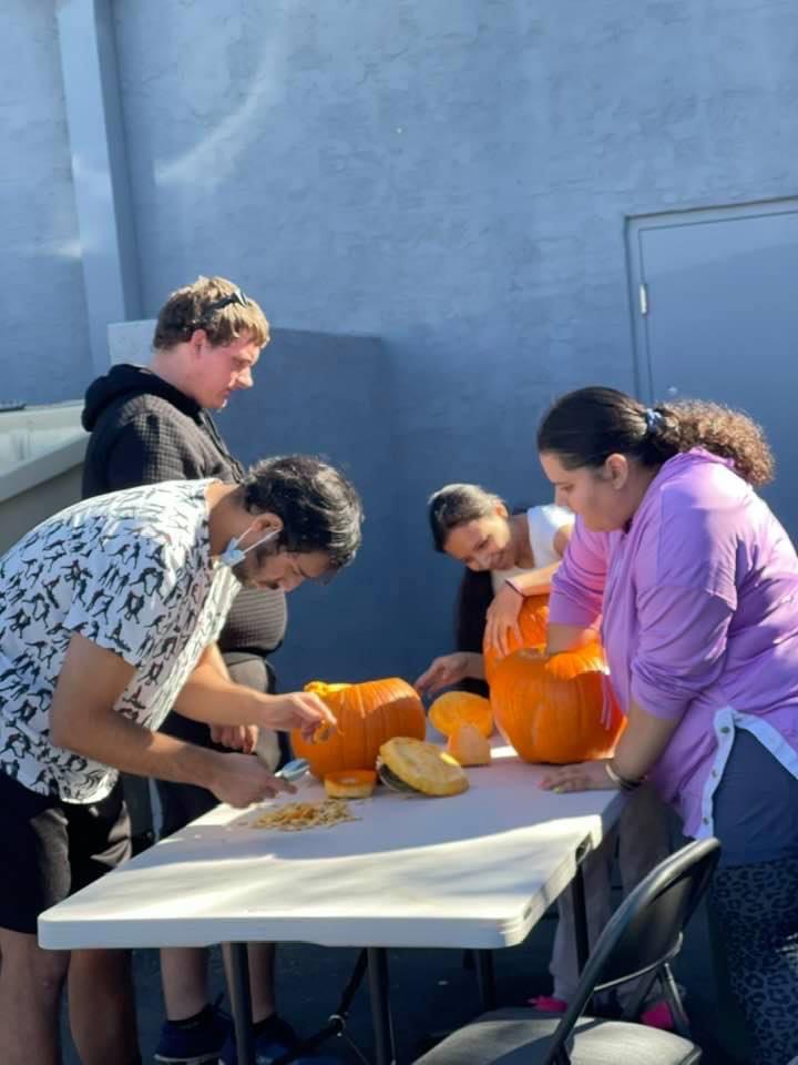 A group of people carving pumpkins on top of a table.