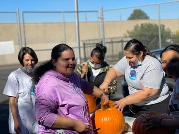 A group of women holding pumpkins on top of a table.