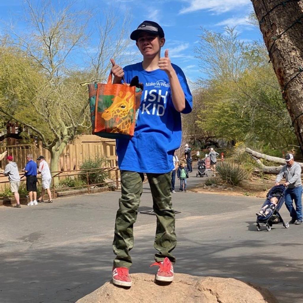 A boy holding a bag in front of trees.